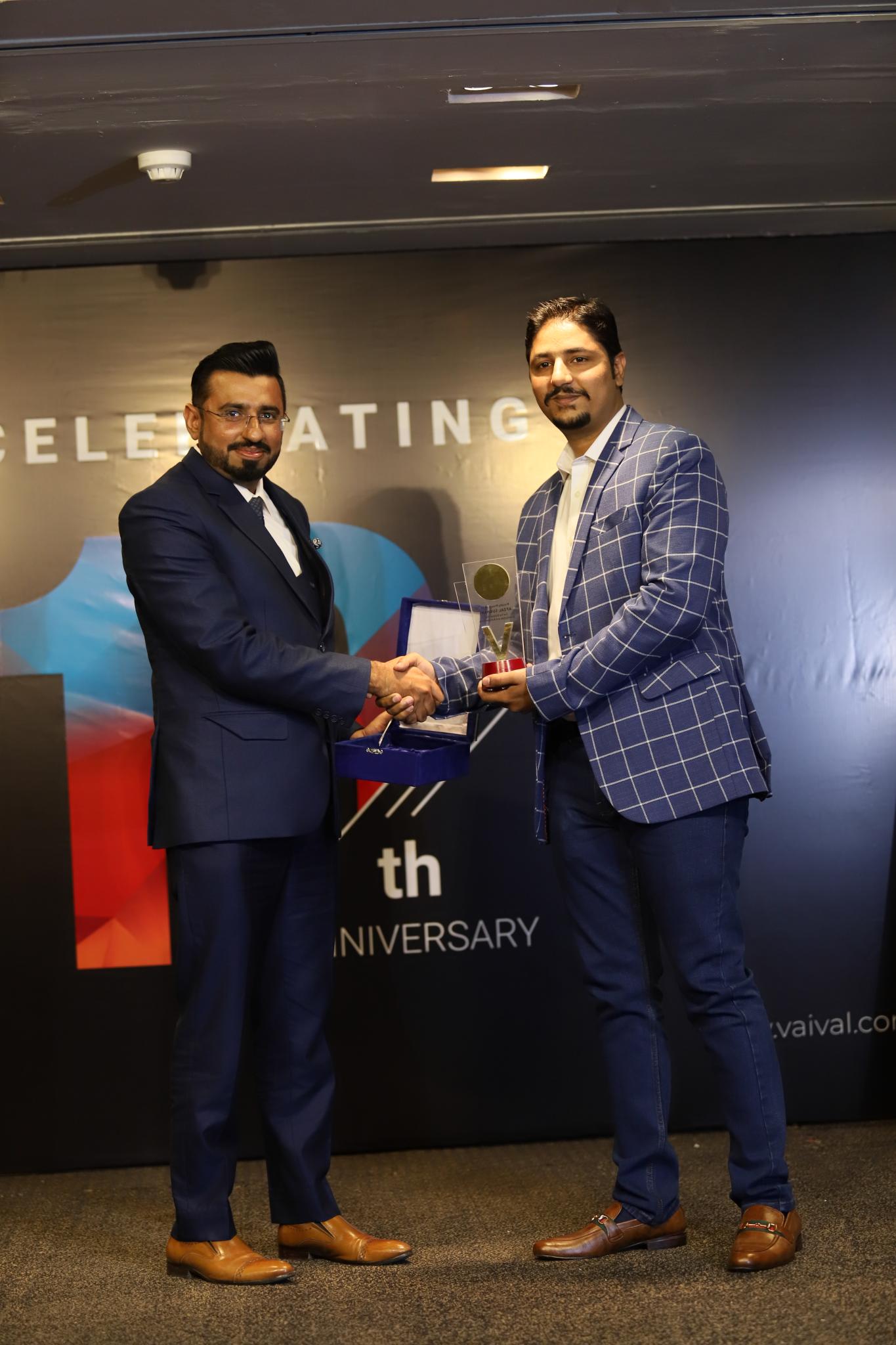 Afzal receiving an award with a handshake